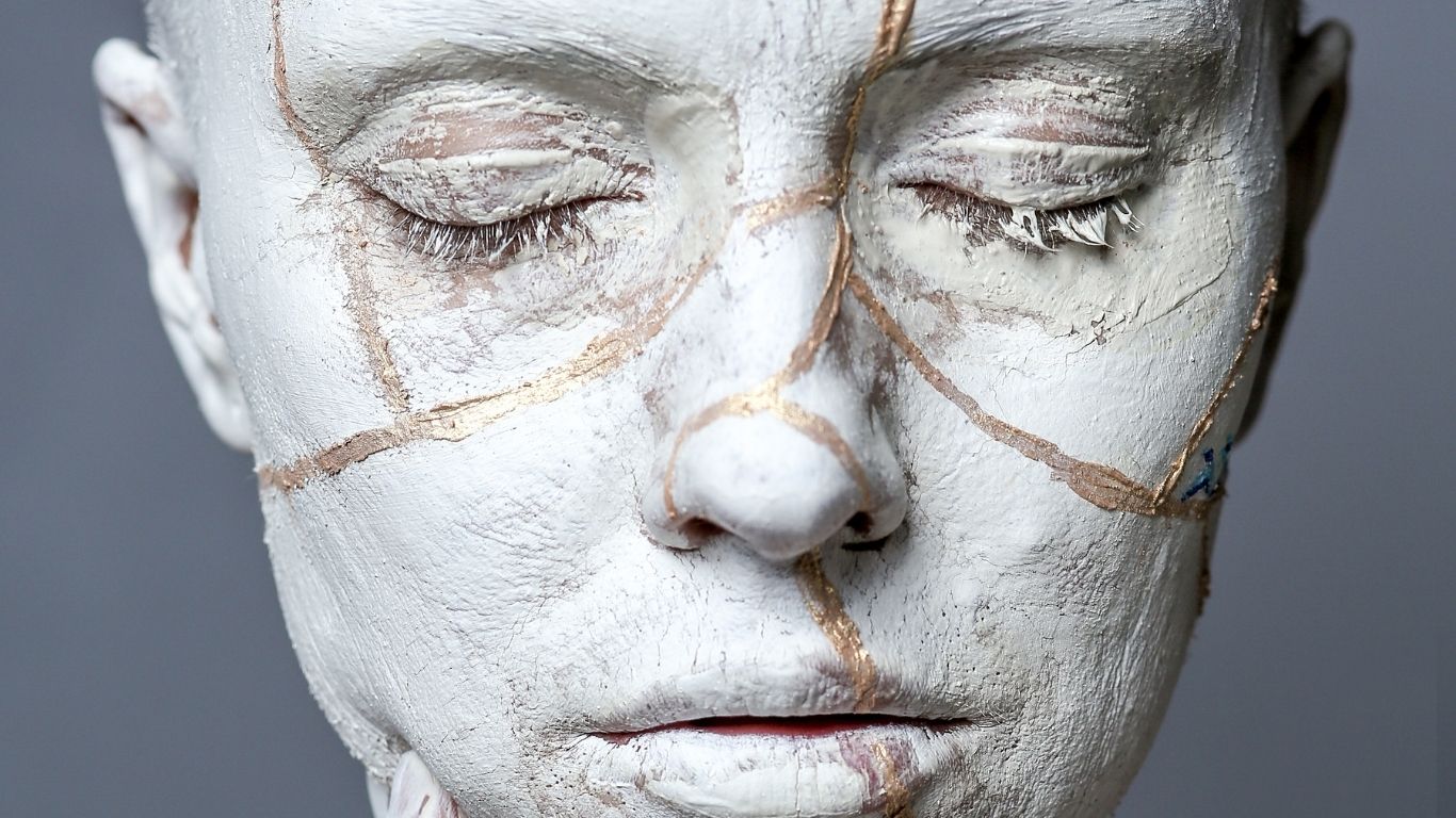 Frauengesicht mit Kintsugi-inspirierten goldenen Rissen als Symbol für authentische Führung und innere Integration.