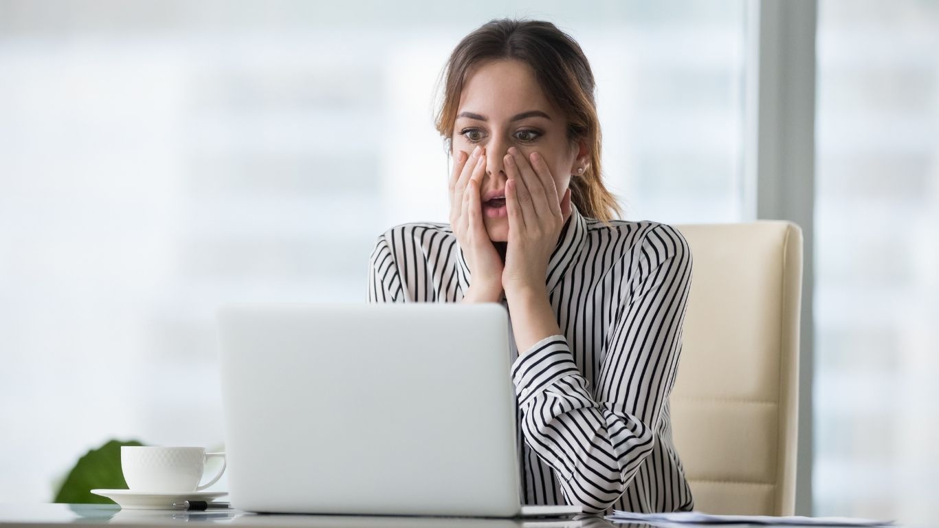 Führungskraft sitzt mit erschrockenem Gesichtsausdruck vor dem Laptop, Hände im Gesicht, sichtbar überfordert – Symbol für Perfektionsdruck und versteckte Führungsfehler.